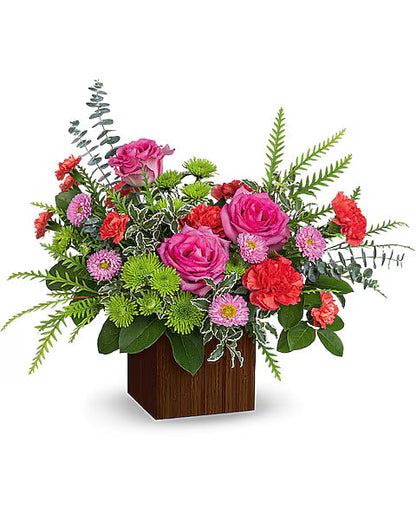 Colorful flower arrangement with pink, red, and green flowers in a wooden box on a white background